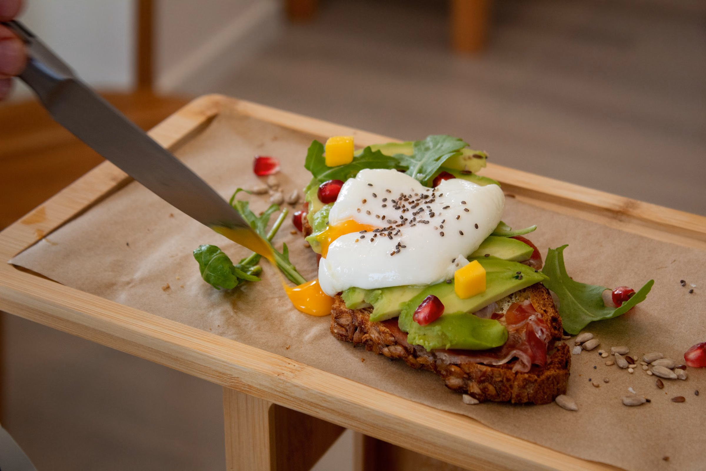 Tostada de aguacate con huevo poché cortándose en la tabla